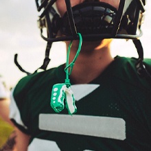 A customized mouthguard hanging from a young person’s helmet during a football game in Evanston