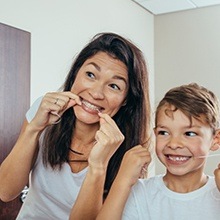 Mother and son flossing teeth together