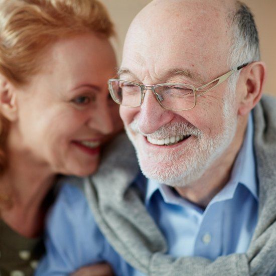 Older man and woman smiling after dental implant supported tooth replacement