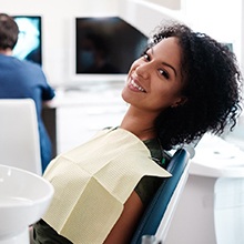 Woman smiling in dental chair while dentist examines digital impressions