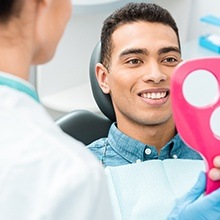 Man looking at smile in mirror during dental checkup and teeth cleaning visit