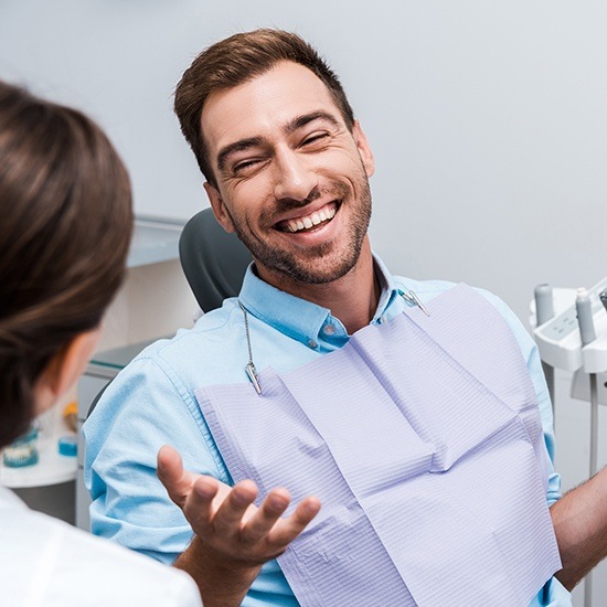 Man in dental chair laughing during preventive dentistry visit