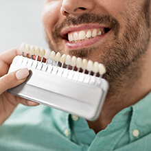 Dentist holding up veneer shades to patient's teeth