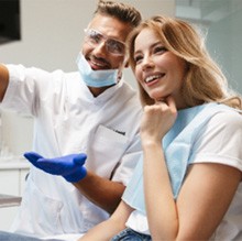 Dentist and patient smiling while looking at screen