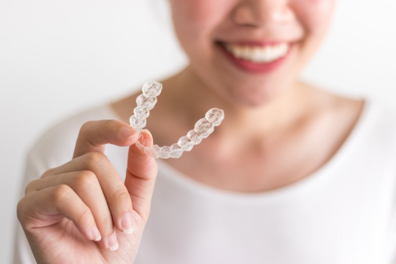 smiling person holding Invisalign